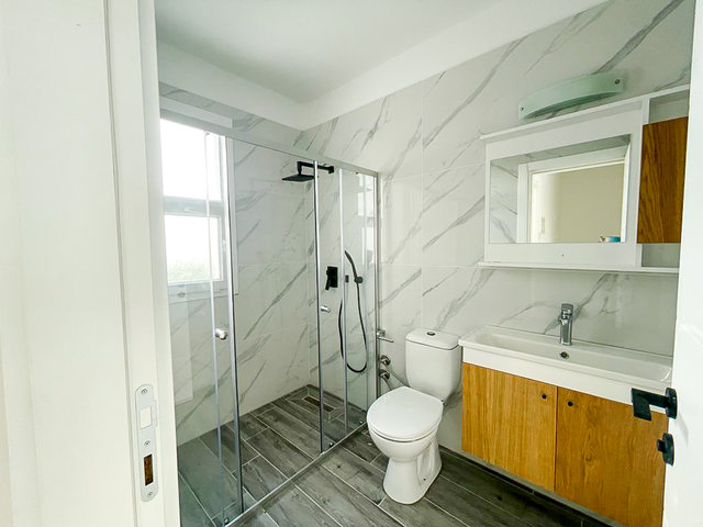 Modern bathroom of 3bedroom villa in Bogaz with grey tiles and wooden cabinets