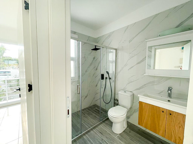 Modern bathroom of 3bedroom villa in Bogaz with grey tiles and wooden cabinets
