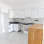 Modern white kitchen with wooden counter and view to balcony