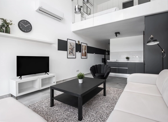 Alt text: Contemporary loft living room with minimalist furniture, TV, and open kitchen in Caesar Cliff.