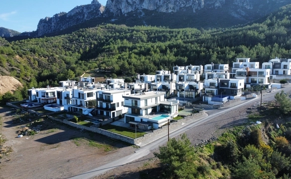 Images showcasing a modern 4-bedroom villa in Karmi, Kyrenia, including exterior architecture, stylish bedrooms, walk-in closet, and panoramic sea views from a hillside location.